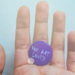 person-holding-purple-badge-you-are-loved-text-printed-1374525