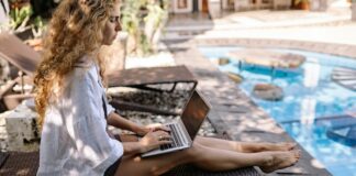 Woman Working By Accommodation Pool As Digital Nomad