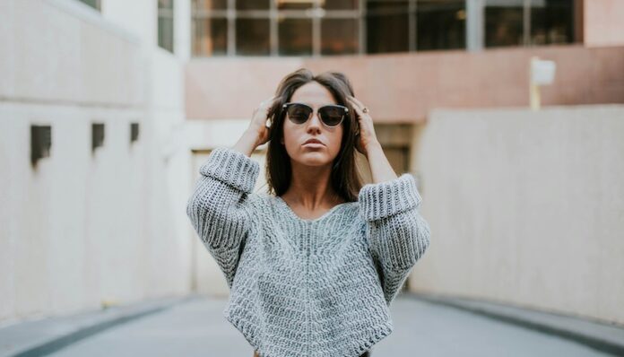 woman-in-grey-knit-shirt-standing-on-roadway-during-daytime